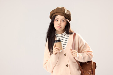 Fototapeta premium Stylish young woman holding takeaway coffee in beret and cardigan