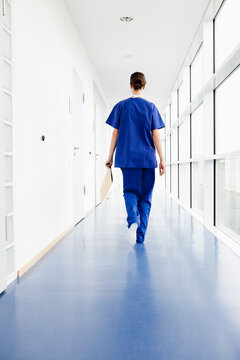 Germany, Bavaria, Diessen am Ammersee, Young doctor walking in corridor with clip board