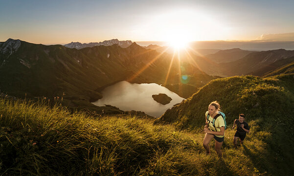 Germany, Allgaeu Alps, man and woman running on mountain trail