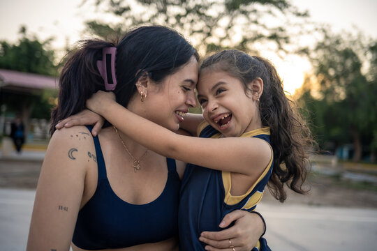 Laughing mother and daughter embracing outdoors