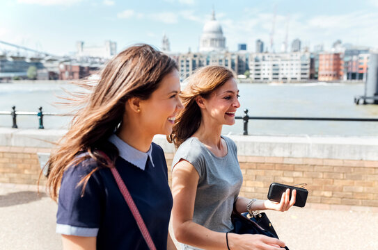 UK, London, two women walking along the banks of the Thames River