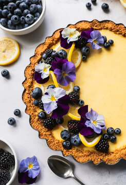 Close up of lemon curd tart with fresh berries and flowers.