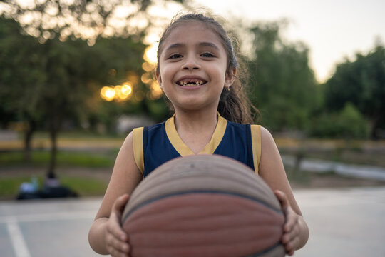 Young girl with a gap tooth holding a basketball