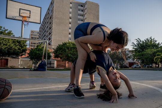 Playful mother and daughter having fun on basketball court