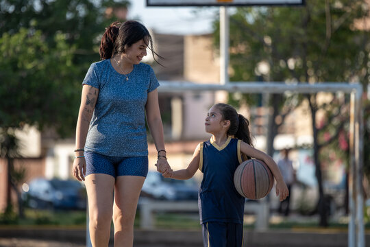 Young girl holding hands with her mother after basketball practice