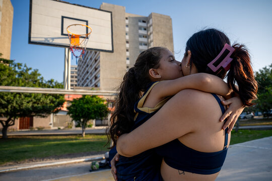 Mother and daughter sharing a hug on a basketball court