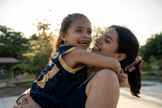 Laughing daughter hugs her mother outdoors