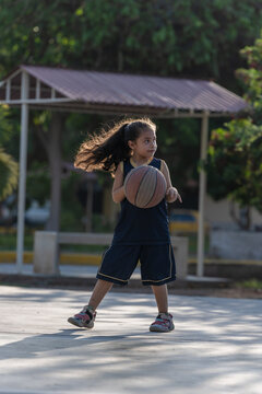 Young girl playing basketball at the park
