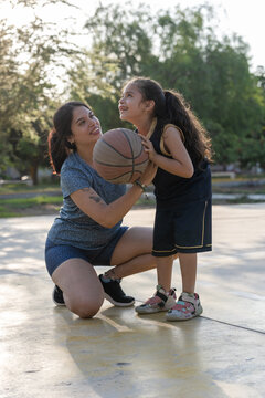 Mother and daughter sharing a happy moment playing basketball
