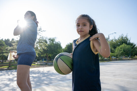 Young girl holding basketball on outdoor court