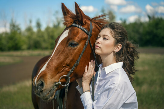 Young woman and horse in a field, blue sky