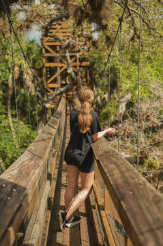 Young woman enjoys view from a forest suspension bridge