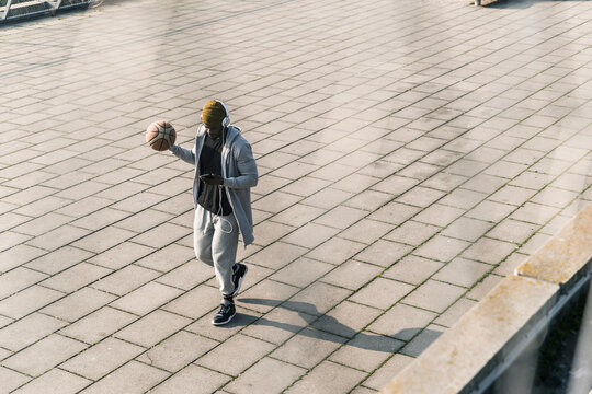 Young man with basketball walking on a square