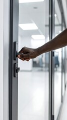 Naklejka premium A person's arm reaching for a door handle in a modern hallway
