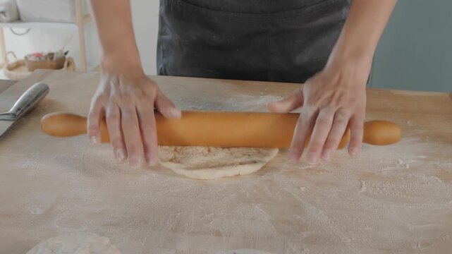 Professional baker rolling dough with a pin