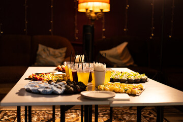 Table laden with assorted appetizers, drinks, and desserts for a party © Тарас Белецкий