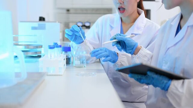 Young scientists conducting research investigations in a medical laboratory, a researcher in the foreground is using a microscope in laboratory for medicine.