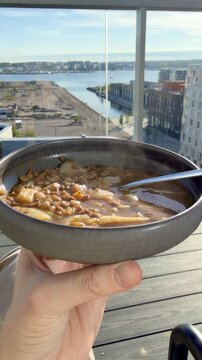 Vertical 4K Steaming Lentil Soup Close Up over J&auml;tk&auml;saari Rooftops