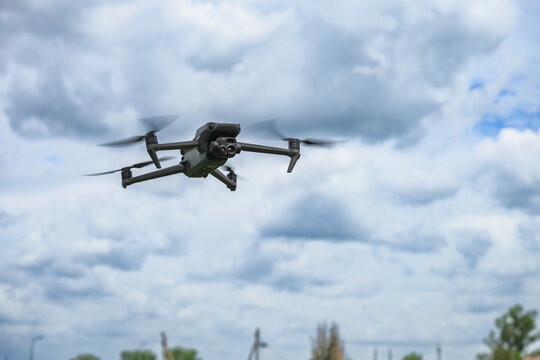 Modern quadcopter drone hovering in the air against dramatic cloudy sky. Unmanned aerial vehicle with camera used for photography, inspection, mapping and technology applications.