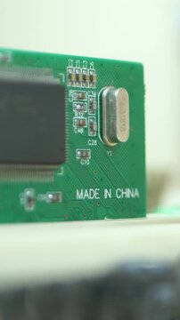Computer engineer fits PCI board into motherboard base. Green plate with Made in China note. Electronic circuit card background. Computer repair and maintenance workshop
