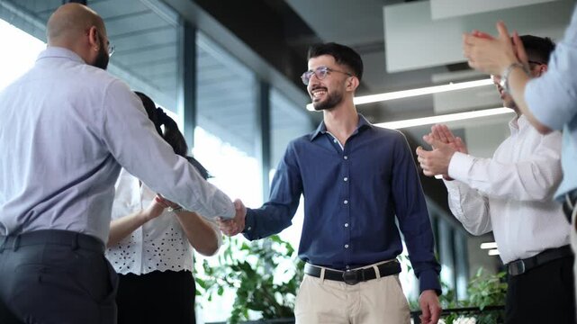 A group of men are standing in a room, one of them is wearing a blue shirt
