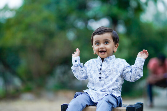 happy indian little boy sitting on traditional cot