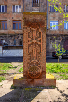 Historic Armenian khachkar stands amidst city greenery