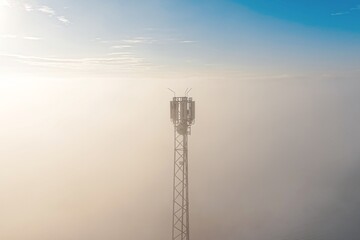 Obraz premium Telecom mast reaching above fog and low clouds