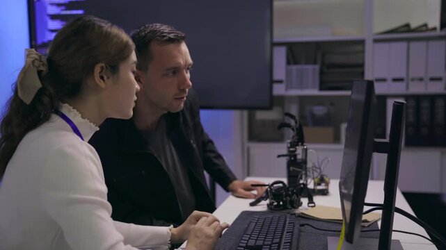 Tech developers collaborating on a robotic device in a lab