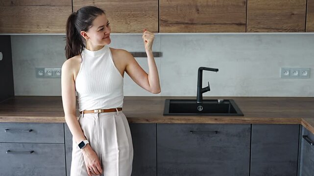 Young woman with apartment keys standing in furnished resale apartment kitchen. Secondary housing purchase and moving into existing property concept