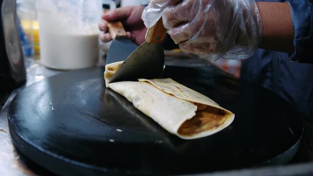 Close up of hands preparing a chocolate banana crepe on a hot plate at a night market in vietnam