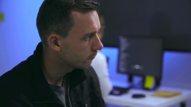 Thoughtful male software developer working with colleague in tech office