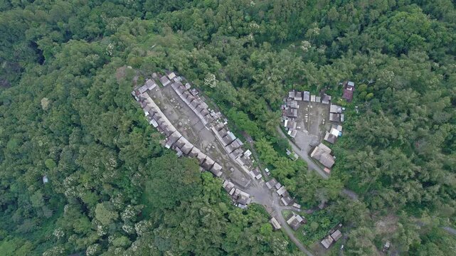 Aerial view of Bena Traditional Village with thatched roofs nestled in a dense tropical forest in Kecamatan Jerebuu, Nusa Tenggara Timur, Indonesia.