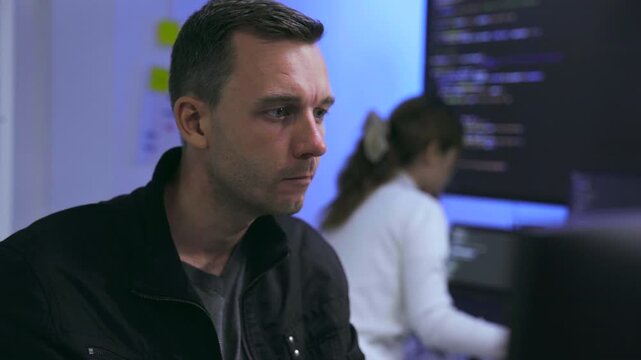 Thoughtful male software developer working with colleague in tech office