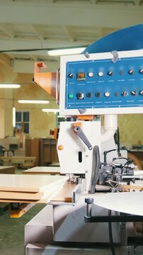 Worker carpenter handles wooden panels on the edging machine on the furniture factory