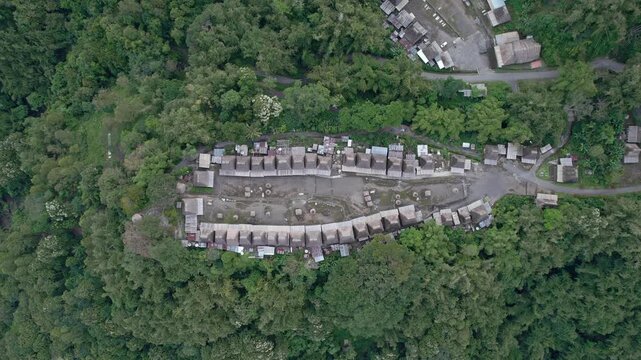 Aerial view of Bena Traditional Village with its iconic thatched-roof houses nestled in the lush green forest of Kecamatan Jerebuu, Nusa Tenggara Timur, Indonesia.