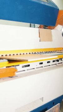Worker carpenter handles wooden board on the edging machine on the furniture factory