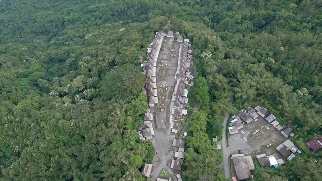 Aerial view of Bena Traditional Village featuring traditional thatched roof houses nestled within a dense tropical forest in Kecamatan Jerebuu, Nusa Tenggara Timur, Indonesia.