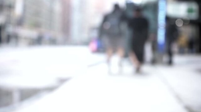 Blurry video clip of people walking across a busy city street intersection with cars and traffic lights.
