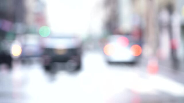 Blurry video clip of people walking across a busy city street intersection with cars and traffic lights.
