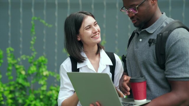 Diverse university students collaborating on a project with laptop outdoor