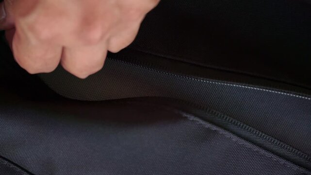 A human hand zipping a black bag. Everyday travel, security, and personal storage concept with modern lifestyle footage.