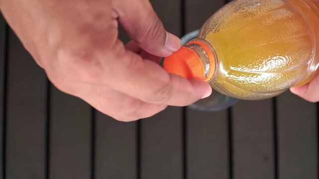 A human hand twists the bottle cap to open a bottle of orange juice. perfect for healthy lifestyle, breakfast, refreshment, and beverage themes.