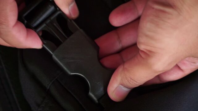Hands unlocking bag strap clip, modern backpack accessory and daily travel lifestyle theme.