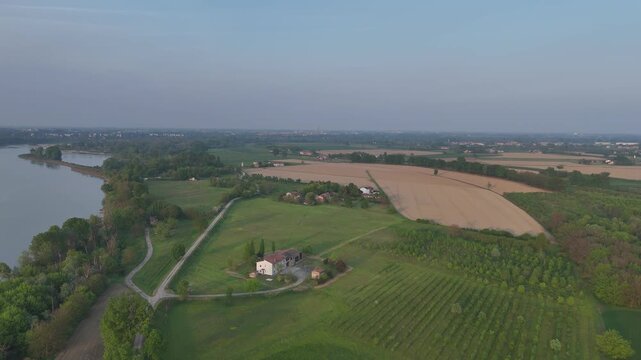 Po River bordering cultivated farmland, orchards and rural fields near Castelvetro Piacentino in Emilia Romagna, Italy, with visible row crops and harvested agricultural plots in the Po Valley, aerial