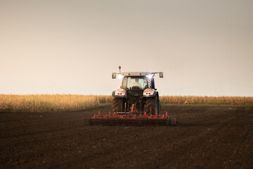 Fototapeta premium Modern tractor working cultivated soil in rural farmland