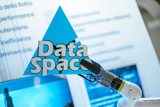 A Fanuc CRX-10iA collaborative robot arm holds a three-dimensional blue triangular sign bearing the text "Data Space" during a tech presentation or trade exhibition.