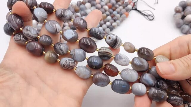 These grey oval banded agate beads feature gold spacers, ideal for creating sophisticated bracelets or layered necklace designs with natural stone charm and elegance