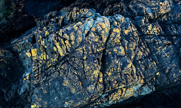 Extremely close up of an interesting hard rock texture with rough surface, nature rock pattern of featuring surface pattern highlights background. Abstract dark nature rock background. 	