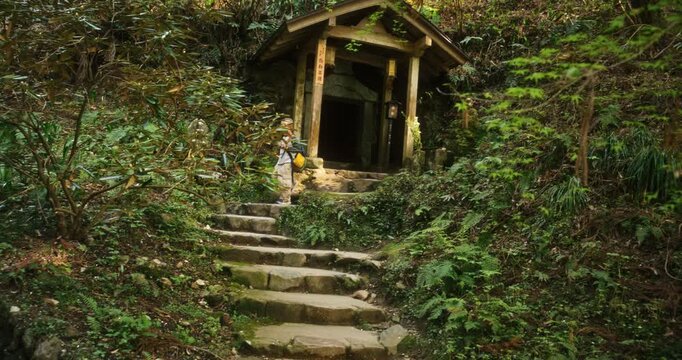 Child with backpack walking out of old wooden gate surrounded by foliage - low, steady cam shot